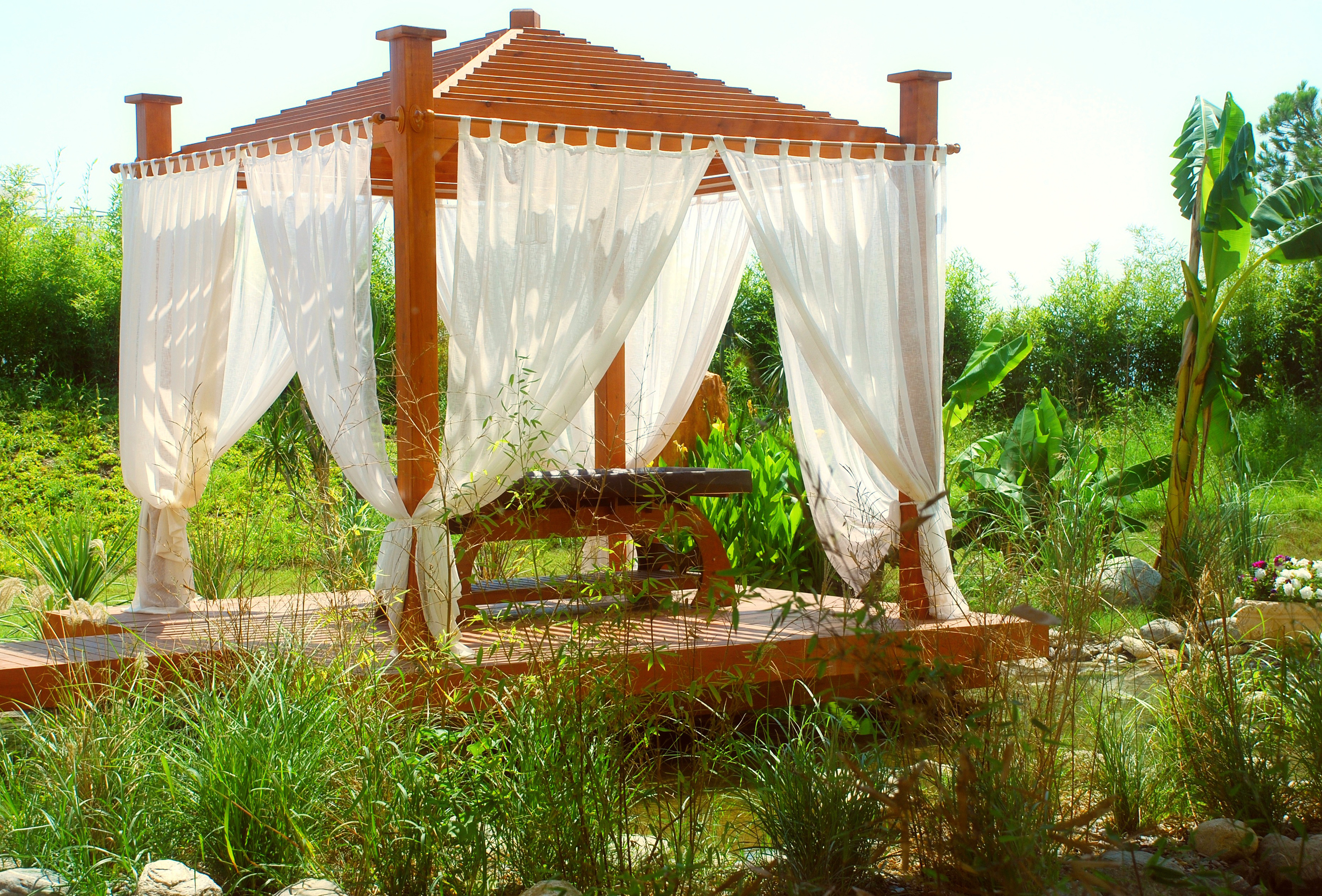 Illuminated blue lanterns hang under a pergola at dusk, creating a warm, inviting ambiance.